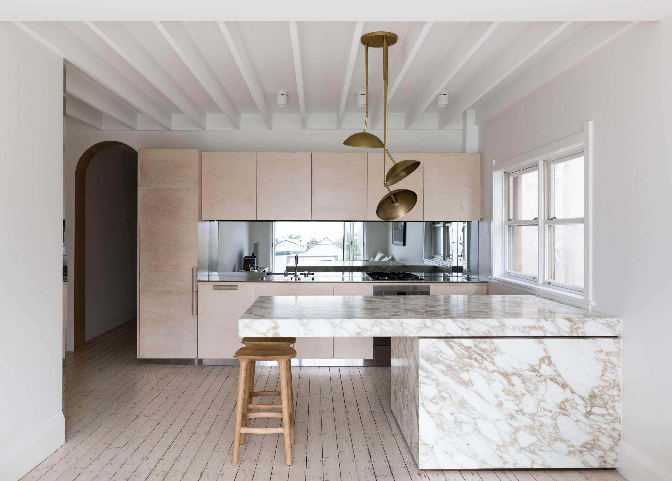 Light timber kitchen with a marble island and brass pendants